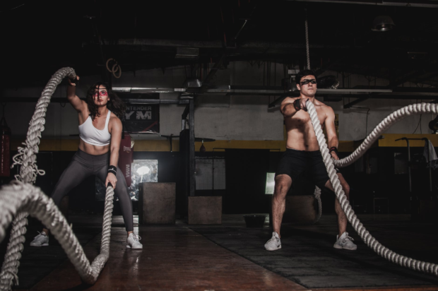 male and female working out with ropes in gym