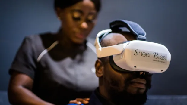 Black female massage therapist giving a black man with a virtual reality headset a massage